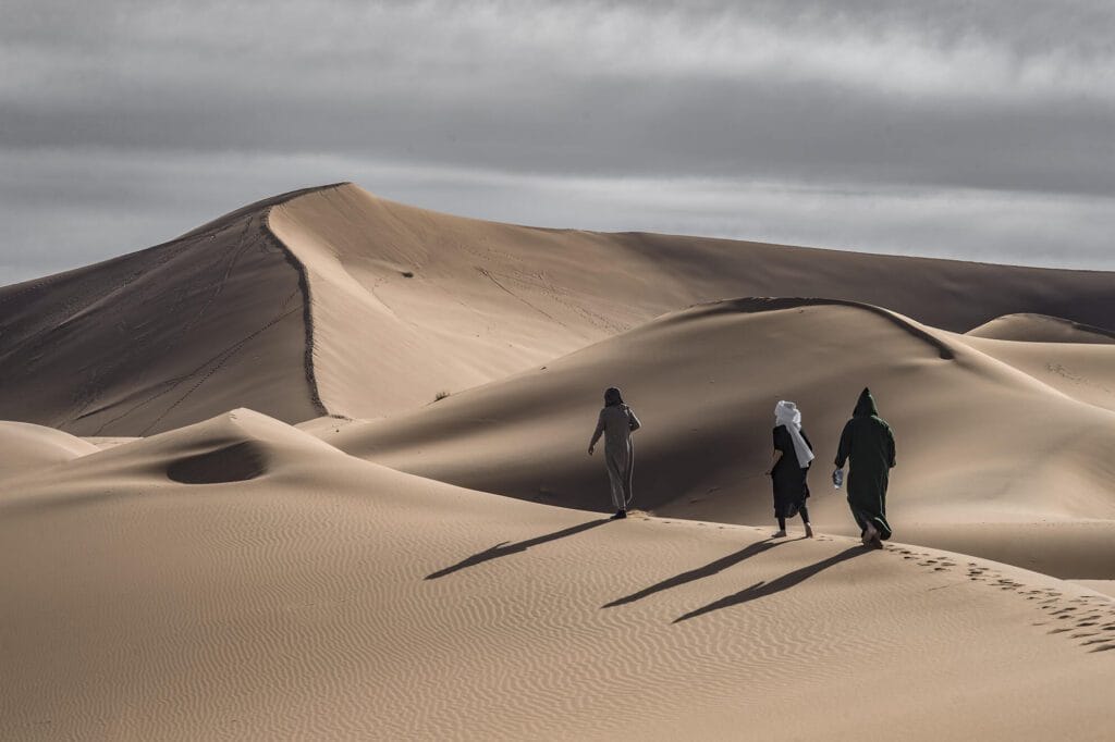 three people walking in the sand dunes
